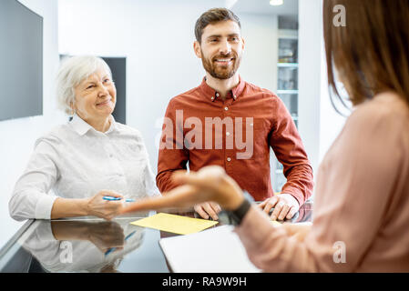 L'homme souriant avec ses hauts mère parler avec réceptionniste dans l'hôpital Banque D'Images