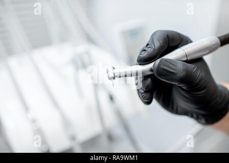 Close-up d'une fraise dentaire avec l'injecteur dans les mains en noir gants médicaux Banque D'Images