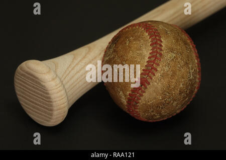 Une vieille et bien utilisé le baseball est affiché à côté d'un nouveau bois, batte de baseball, sur un fond noir. Banque D'Images