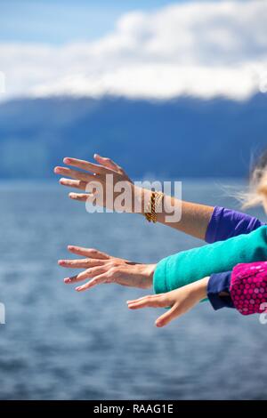 Mains de femmes et d'enfants sur un fond de mer et montagne Banque D'Images