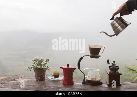 Tasse de café du matin avec le Rotary rectifieuse de café et pot de fleurs sur la table en bois avec fond de montagne au lever du soleil et de la mer de brouillard, de droit avec co Banque D'Images