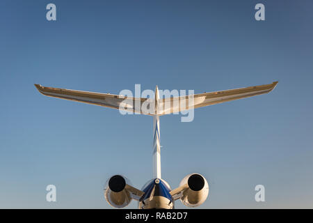Queue d'un avion à réaction d'affaires personnelles éclairées par le chaud soleil couchant contre un ciel bleu, symétrique Banque D'Images