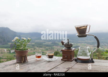 Tasse de café du matin avec le Rotary rectifieuse de café et pot de fleurs sur la table en bois avec fond de montagne au lever du soleil et de la mer de brouillard, de droit avec co Banque D'Images