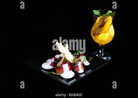 Verre d'hiver avec des morceaux d'orange et d'épices sur un fond noir. Restaurant. Banque D'Images