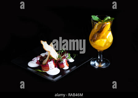 Verre d'hiver avec des morceaux d'orange et d'épices sur un fond noir. Restaurant. Banque D'Images