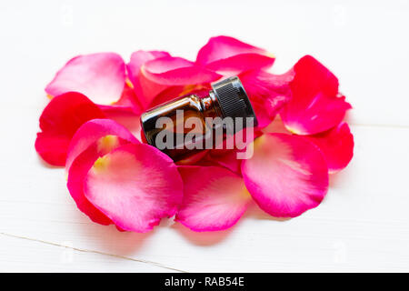 L'huile essentielle de pétales de rose sur fond de bois blanc. Banque D'Images