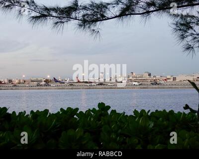 L'Aéroport International de Miami vu à travers une lagune et la Dolphin Expressway au crépuscule, Miami, Floride, USA. Banque D'Images