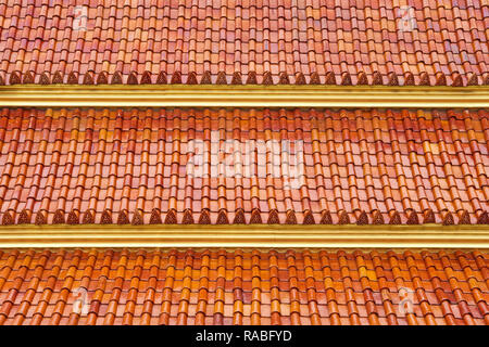 Le toit d'un temple bouddhiste à Bangkok, Thaïlande, couverts de l'orange-brun traditionnel des bardeaux et des ornements représentant le Bouddha frontière Banque D'Images
