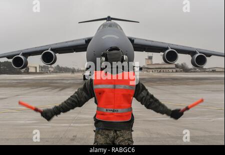 Airman Senior Earl Shelton, 721e Escadron de maintenance d'aéronefs technicien de maintenance aéronautique, marshals un C-5M Super Galaxy en place à la base aérienne de Ramstein, en Allemagne, le 24 janvier 2017. Après avoir été en place, 721e AMXS aviateurs calé les roues, branché sur un générateur, vérifié la pression des pneus, l'huile rempli, et plein de l'avion. En moyenne, la 721e AMXS inspecte, services, réparations et 30 appareils en une seule journée, dans le cadre de la 521e escadre Opérations de mobilité aérienne à Ramstein. Banque D'Images