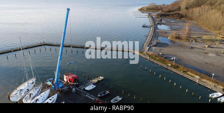 03 janvier 2019, Mecklembourg-Poméranie-Occidentale, Lannilis : le poisson vendu 'Coupe' Kehrwieder est levé avec une grue dans le port de Lannilis. La faucheuse a coulé en partie après la tempête et le poser sur le sol. (Photographie aérienne avec drone) Photo : Stefan Sauer/dpa-Zentralbild/dpa Banque D'Images