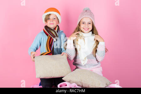 Les enfants garçon et fille réchauffer avec des oreillers et des chapeaux. Restez au chaud et confortable. Réchauffer votre hiver porter avec mignon et confortable accessoires. Frères et sœurs portent des chapeaux d'hiver au chaud assis sur fond rose. Banque D'Images