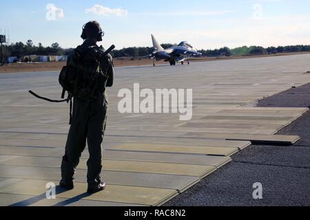 Le Major Aaron Hamblin observe un AV-8B Harrier comme l'instruction des pilotes à l'intérieur de préparer pour le décollage à bord du Marine Corps d'atterrissage auxiliaire Bogue, N.C., 19 janvier 2017. L'Escadron 203 attaque Marine, Marine Aircraft Group 14, 2nd Marine Aircraft Wing, forme des pilotes à décoller de terre, sur et voler dans tout lieu, y compris l'ICLÉM et limiter les navires et les terrains spacieux. Hamblin est un pilote instructeur avec TMAV-203. Banque D'Images