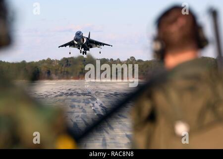 Des pilotes-instructeurs avec attaque Maritime Training Squadron 203, Marine Aircraft Group 14, 2nd Marine Aircraft Wing, observer un AV-8B Harrier de l'atterrissage sur la piste à l'atterrissage auxiliaire Marine Corps Bogue, N.C., 19 janvier 2017. Comme le seul site de la côte est qui offre aux pilotes du Corps des marines de l'opérateur sur le terrain pratique d'atterrissage, l'aérodrome est essentielle à l'amélioration de la préparation des missions expéditionnaires par la formation des pilotes d'atterrir sur des porte-avions. L'aérodrome est composé de pistes construites à partir de panneaux en aluminium, qui peut être démonté et reconstruit n'importe où dans le monde en l'espace de quelques jours. Banque D'Images