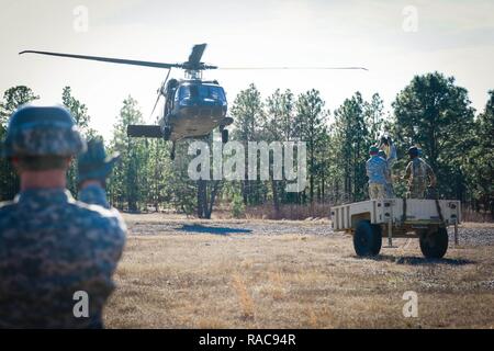 Un soldat de l'École d'assaut aérien DeGlopper, XVIII Airborne Corps guides dans un UH-60 Black Hawk affecté à la 2ème bataillon d'hélicoptères d'assaut, 82e Brigade d'aviation de combat qu'elle prépare pour connecter un remorque cargo charge sous élingue sur Fort Bragg, N.C., Jan 19. Banque D'Images