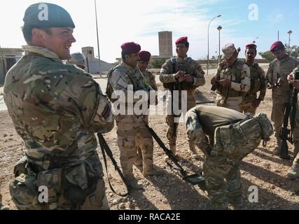 Formateurs britanniques à partir de la 4e Bataillon, 'Les fusils", de plaisanter avec les soldats iraquiens à partir de la 7e Division de l'armée iraquienne pendant le chargement de magazines avec des munitions à blanc pendant l'assaut du peloton de mouvement, une partie de leur formation à culminant Al Asad Air Base, l'Iraq, le 15 janvier 2017. Formation à renforcer les capacités des partenaires nationaux fait partie intégrante de la Force opérationnelle interarmées - Fonctionnement de l'effort pour résoudre inhérent de former le personnel des forces de sécurité irakiennes. Les GFIM-OIR est la Coalition mondiale pour vaincre ISIL en Iraq et en Syrie. Banque D'Images