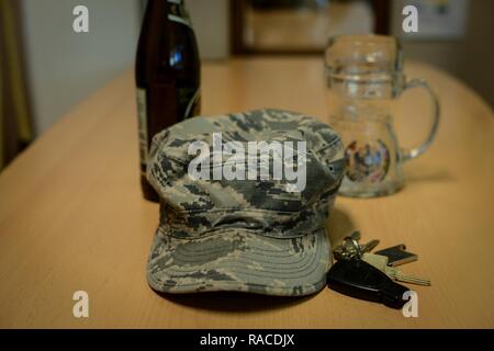 Une bataille à motifs uniforme froissé d'un membre de la cap se trouve sur une table à côté d'une bouteille de bière , jeu de clés, et beer mug à base aérienne de Ramstein, en Allemagne, le 20 janvier 2017. L'Airman contre l'alcool au volant programme est disponible dans de nombreuses bases de l'Armée de l'air et vise à prévenir les cas de DUI chez les aviateurs. Banque D'Images