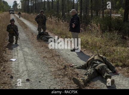 HN Justin Yammoto jette sur le sol comme une victime simulée comme Marines avec 2e bataillon amphibie assaut écoutez John Galloway, un contre-Dispositif explosif avec l'instructeur de l'École de mécanicien de marine, demandez à la façon de mieux réagir à la rencontre d'un IED au cours d'une opération de convoi CIED monté au camp Lejeune, N.C., 11 janvier 2017. La formation est destinée à familiariser les Marines avec des procédures pour mieux fonctionner sous la menace de l'IED, tout en conservant le contrôle tactique de leur situation et de leur environnement. Yammoto Corpsman est un avec l'appareil. Banque D'Images