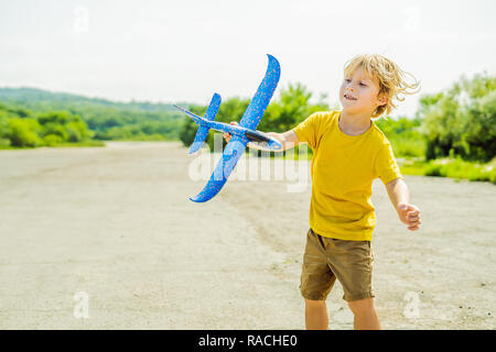 Happy kid Playing with toy airplane contre l'ancienne piste d'arrière-plan. Concept de voyager avec des enfants Banque D'Images