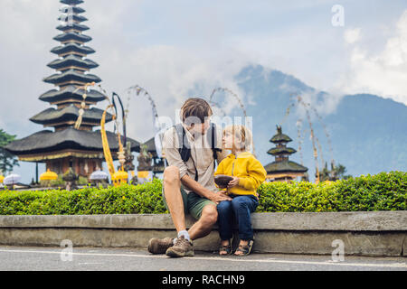 Père et fils dans l'arrière-plan de Pura Ulun Danu Bratan, Bali. Hindu Temple entouré de fleurs sur le lac Bratan, Bali. Grand temple de l'eau Shivaite à Bali, Indonésie. Temple hindou. Voyager avec des enfants concept Banque D'Images