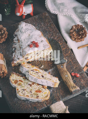 Stollen traditionnel cuit au four gâteau européen avec des écrous et des fruits confits saupoudrés de sucre en poudre et couper en morceaux sur une planche de bois brun, top vi Banque D'Images