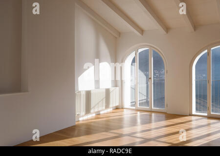 Salle vide avec grande fenêtre donnant sur le lac. Poutres antiques sur le plafond d'un appartement rénové Banque D'Images