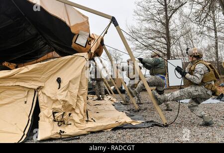 Aviateurs affecté à la 435ème Groupe d'intervention d'urgence travaillent ensemble pour construire une tente pendant l'exercice austère Forge sur base aérienne de Ramstein, en Allemagne, le 1 février 2017. Au cours de l'exercice, les aviateurs planifié que l'équipement serait utilisé et qui serait aller, préparé l'équipement et de personnel, traitée par le 86e Escadron de préparation logistique de l'installation de la cellule de préparation au déploiement, et mis en place des tentes et de l'équipement déployé dans une simulation de l'emplacement. Le CRG 435 ont participé à l'exercice d'exercer leur capacité de déployer dans un délai de 72 heures. Banque D'Images