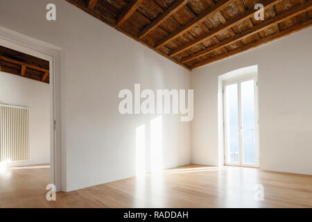 Salle vide avec grande fenêtre donnant sur le lac. Poutres antiques sur le plafond d'un appartement rénové Banque D'Images