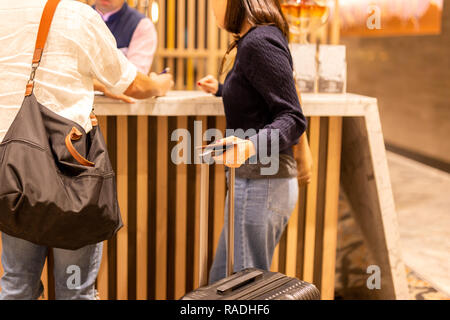 Woman holding passport avec valise tandis que mari signature document à l'hôtel. Banque D'Images