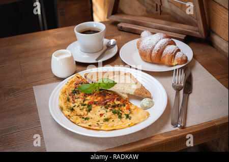 Le petit-déjeuner. Omelette aux verts, croissant et café Banque D'Images