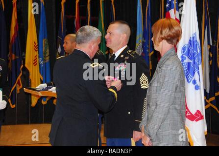 Le brig. Le général James Bonner, général commandant, 20e d'armes chimiques, biologiques, radiologiques, nucléaires, des explosifs (CBRNE), axes de commande la médaille de la Légion du Mérite de la commande sur le Sgt. Le major Kenneth Graham's uniforme que son conjoint, melon, les regarde. Graham a pris sa retraite de l'armée américaine après 31 ans de service au cours d'une cérémonie de la retraite le 14 décembre sur Aberdeen Proving Ground, au Maryland. Banque D'Images