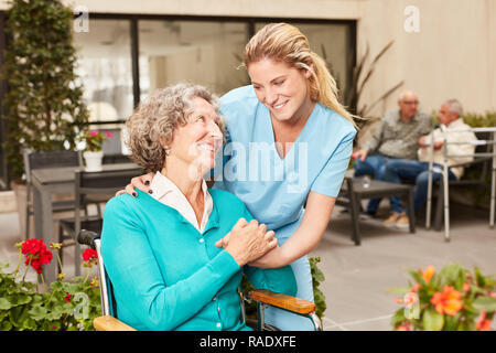 Le fournisseur de soins s'occupe de senior woman sur terrasse dans maison de retraite Banque D'Images