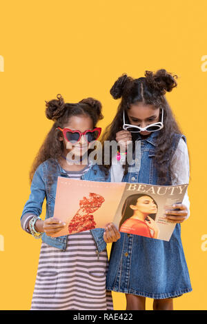 Cute belle soeurs la lecture d'articles ensemble dans le magazine Banque D'Images