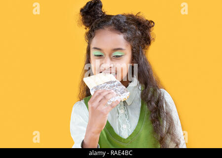 Portrait of a happy cheerful girl biting une barre de chocolat Banque D'Images