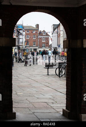 Chichester, Royaume-Uni - 06 octobre 2018 : Shoppers le long de la rue du Nord comme vu à travers une arche de Chichester de ville Banque D'Images