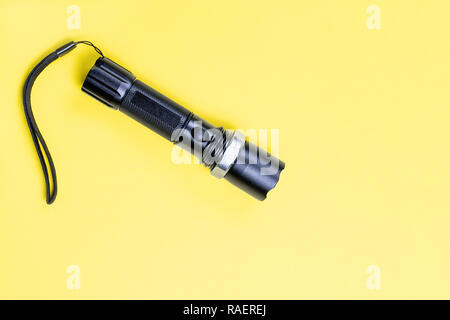 Blacc metal small tactical falshlight isoltaed sur fond jaune. Banque D'Images