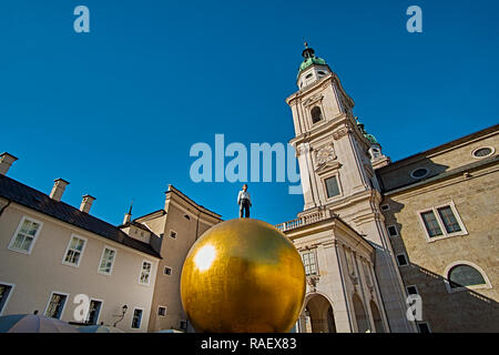 L'homme sur le ballon d'or en Kapitelplatz (chapitre Square), belle journée ensoleillée avec vue sur la cathédrale de Salzbourg (Dom zu Salzburg) à Salzbourg, en arrière-plan Banque D'Images