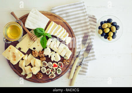 Assiette de fromage : Parmesan, cheddar, gouda, gorgonzola, brie et d'autres avec des noix, des olives et du miel sur planche de bois sur fond blanc. Appetiz savoureux Banque D'Images