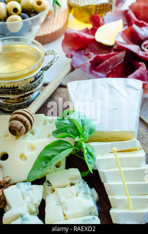 Assiette de fromages : Brie, Parmesan, cheddar, gouda, gorgonzola et d'autres avec des noix et du miel sur planche de bois. De savoureux apéritifs avec différents types de c Banque D'Images