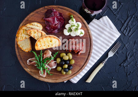 Vin antipasti italiens des en-cas. Fromage Mozzarella, olives méditerranéennes, Prosciutto di Parma, bresaola, tomates séchées au soleil et des toasts sur boa en bois Banque D'Images
