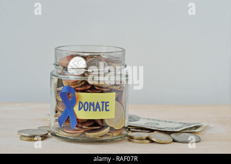 Argent pot plein de coins avec du ruban bleu et de donner à l'étiquette - Notion d'organisme de bienfaisance du cancer de la prostate et du fonds de recherche Banque D'Images