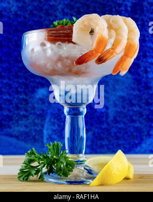 Un cocktail de crevettes : vue latérale du verre de margarita avec crevette accroché sur l'extérieur du verre. Sauce cocktail à l'intérieur de la coupe avec de la glace. À la base du verre de citron Banque D'Images