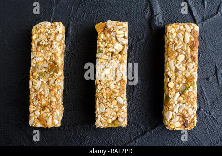 Healthy dessert des collations. Aliments diététiques de remise en forme. Trois barres granola fait maison avec des flocons d'avoine, sésame, tournesol et graines de citrouille, les raisins secs, le miel sur le Banque D'Images