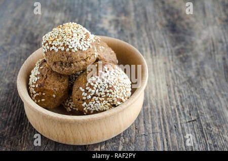 Des collations aux céréales dessert sucré. Aliments diététiques de remise en forme. Banana-biscuits au miel et saupoudré de graines de sésame dans le bol en bois rustique sur l'ancien conseil. Ve Banque D'Images