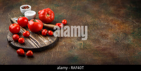 Tomate fraîche, vieux couteau, sel et poivre sur planche de bois. L'espace pour le texte. Bannière longue et large Banque D'Images