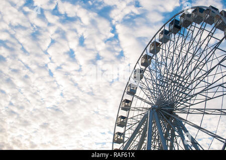 Une partie de la grande roue sur fond de ciel bleu nuageux dans un parc d'amusement. Banque D'Images