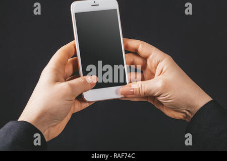 Téléphone mobile dans les mains sur un fond noir Banque D'Images