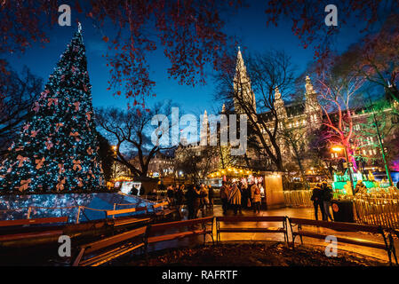 Photo de nuit des marchés de Noël au Burgtheater, éclairé de l'arbre décoré avec des lumières colorées, de l'hôtel de ville en arrière-plan Banque D'Images