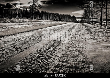 Désolé désertes routes sinueuses avec neige et glace disparaissant dans la distance Banque D'Images