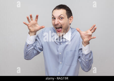 Portrait d'homme en soie beau drôle étonné dans classic light blue shirt debout avec les mains posées et fou, face crier. Piscine studio Banque D'Images