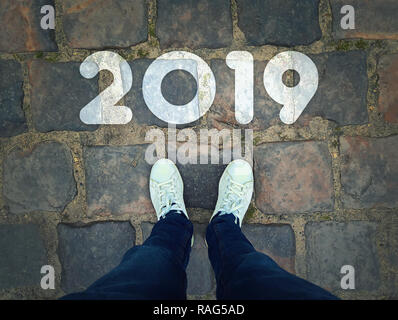 Vue de dessus d'un homme en blanc sneakers vintage sur fond des chaussées debout à côté de 2019 ligne de départ. Démarrage d'un nouveau défi de l'année concept. Banque D'Images